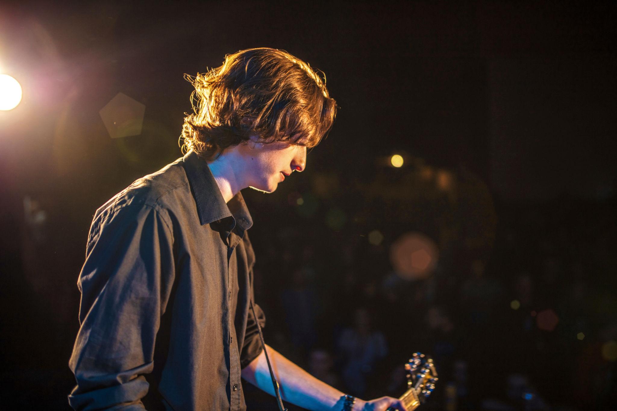 Teen musician performing on stage with guitar
